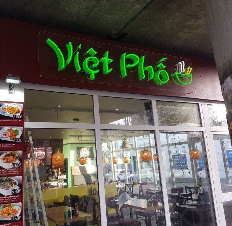 Schaufenster des vietnamesischen Restaurants „Viet Pho“ mit neongrünem Schild und Menüfotos.