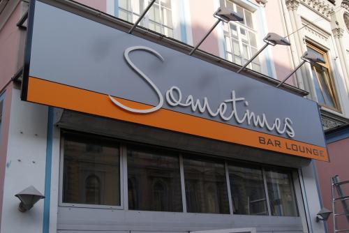 Schild „Sometimes Bar Lounge“, grau und orange, über dem Eingang.