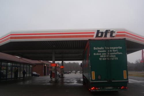 Ein grüner LKW an einer BFT-Tankstelle, bewölkter Tag. Das Verdeck hat rote und weiße Streifen.