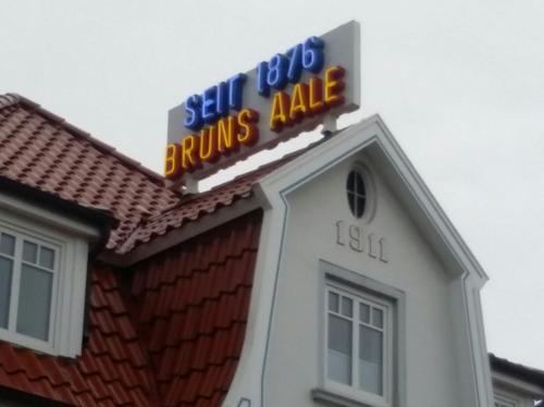 Schild an einem Gebäude: „Seit 1876 Bruns Aale“ in Neonlicht; Datum „1911“ auf dem Gebäude.