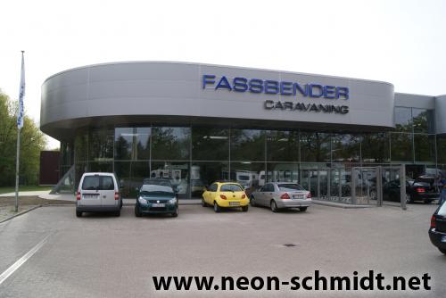 Gebäude von Fassbender Caravaning mit davor geparkten Autos; blau-graue Fassade mit großen Glasfenstern.