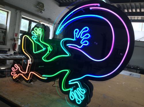 Neon-Gecko-Schild, bunte Lichter, die eine Eidechse auf schwarzem Hintergrund umreißen.