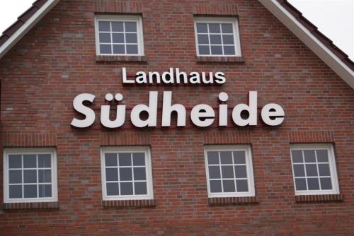 Backsteingebäude mit Schild „Landhaus Südheide“ über den Fenstern.