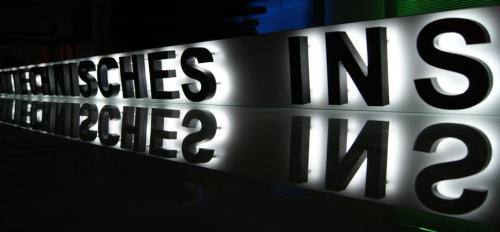 Hinterleuchtetes Schild mit den Worten „TECHNISCHES“ und „INS“ darunter.
