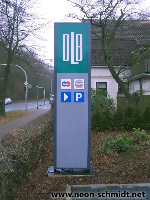 Schild der OLB-Bank, blaugrün und grau, mit Zahlungs- und Parksymbolen.