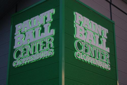 Grünes Schild für Paintball Center Cloppenburg mit weißer Schrift und grüner Neonbeleuchtung.