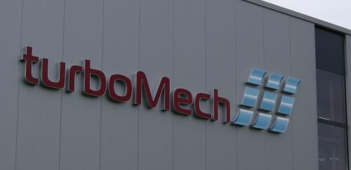 „turboMech“-Logo auf einem Gebäude, rote Buchstaben mit blauem Emblem rechts.