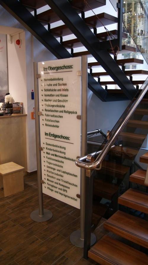 Schild mit einer Dienstleistungsauflistung auf Deutsch neben einer Treppe mit braunen Holzstufen.