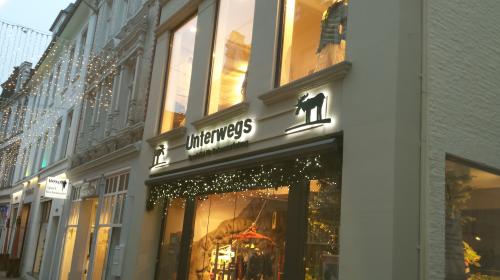 Schaufenster mit „Unterwegs“-Schild und Weihnachtsbeleuchtung.