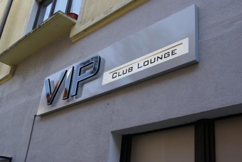 „VIP Club Lounge-Schild an einem hellgrauen Gebäude. Silberne Buchstaben mit einem weißen Rechteck.“