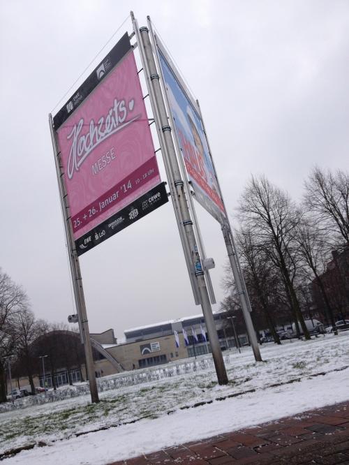 Rosa und blaues Schild für die „Techcats“-Veranstaltung in einer verschneiten Umgebung im Freien.