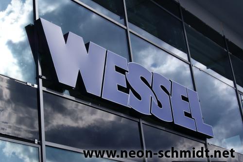 „WESSEL“-Logo in Blau auf einem Gebäude mit reflektierenden Glasfenstern.