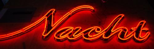 Neonschild, rot leuchtend, mit der Aufschrift „Nacht“.