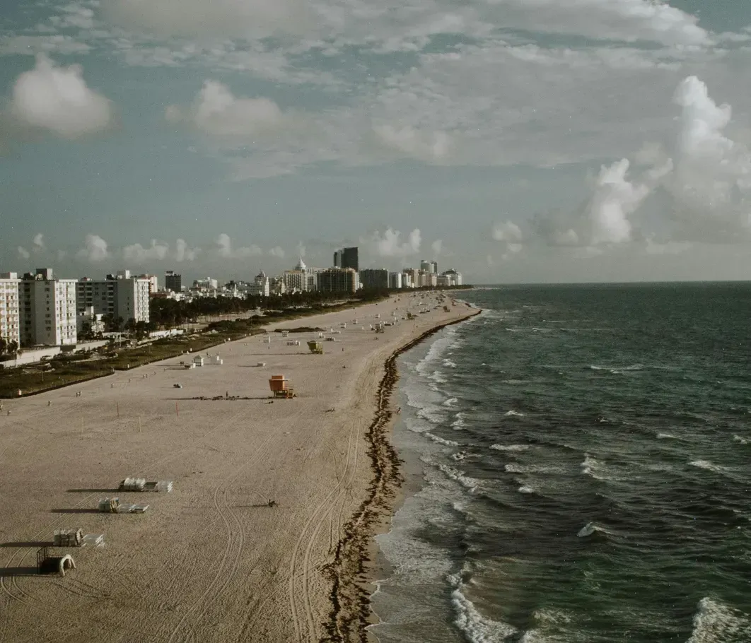 An aerial view of a beach with a city in the background.