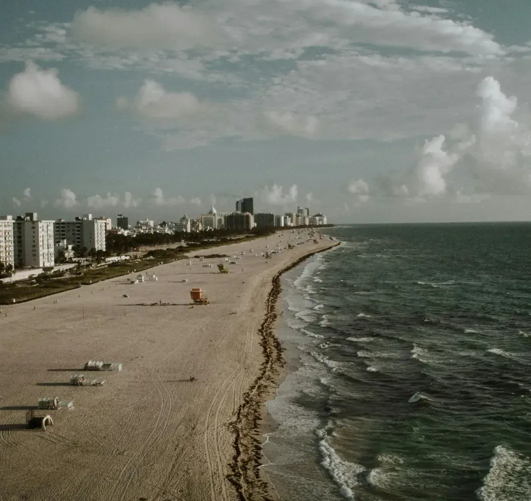 An aerial view of a beach with a city in the background.