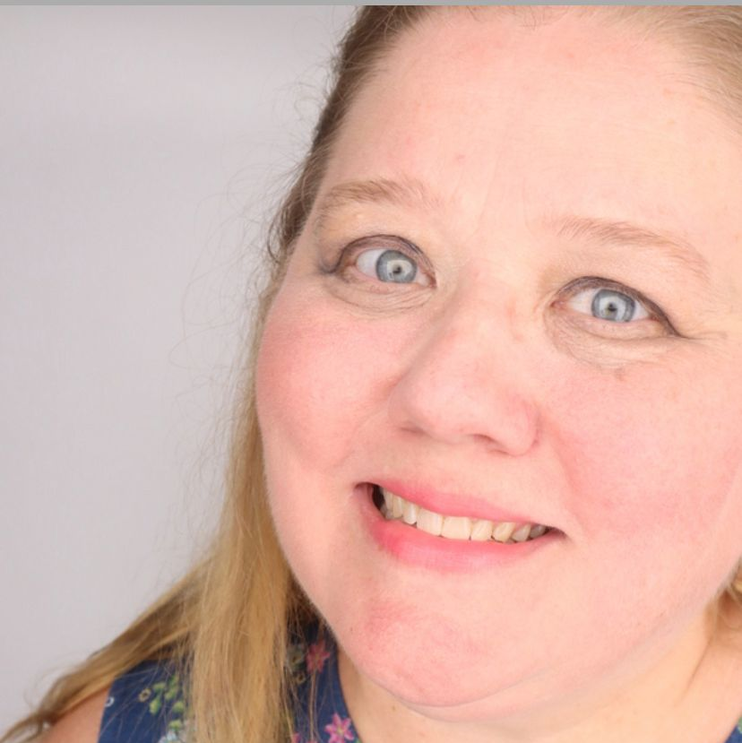 Woman with fair skin and blue eyes smiling, angled headshot.