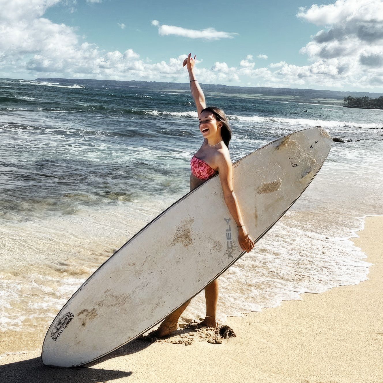 Een meisje in bikini houdt een surfplank vast op het strand