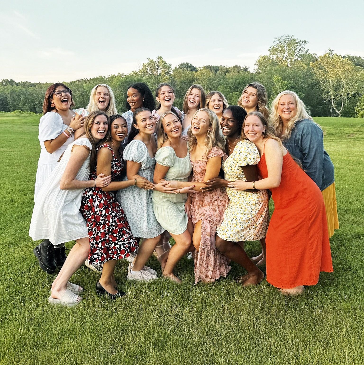 Een groep vrouwen poseert voor een foto in een grasveld.