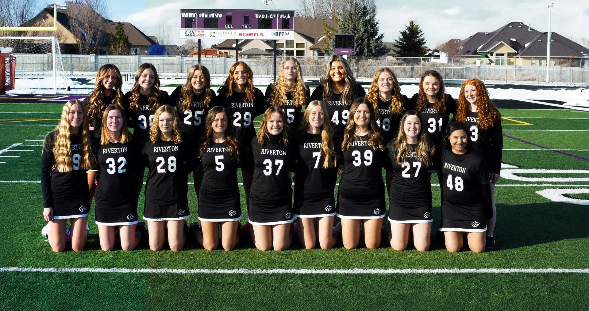 Een groep meisjes poseert voor een teamfoto op een veld.