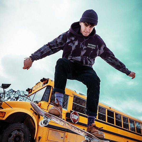 Een man rijdt op een skateboard bovenop een gele schoolbus