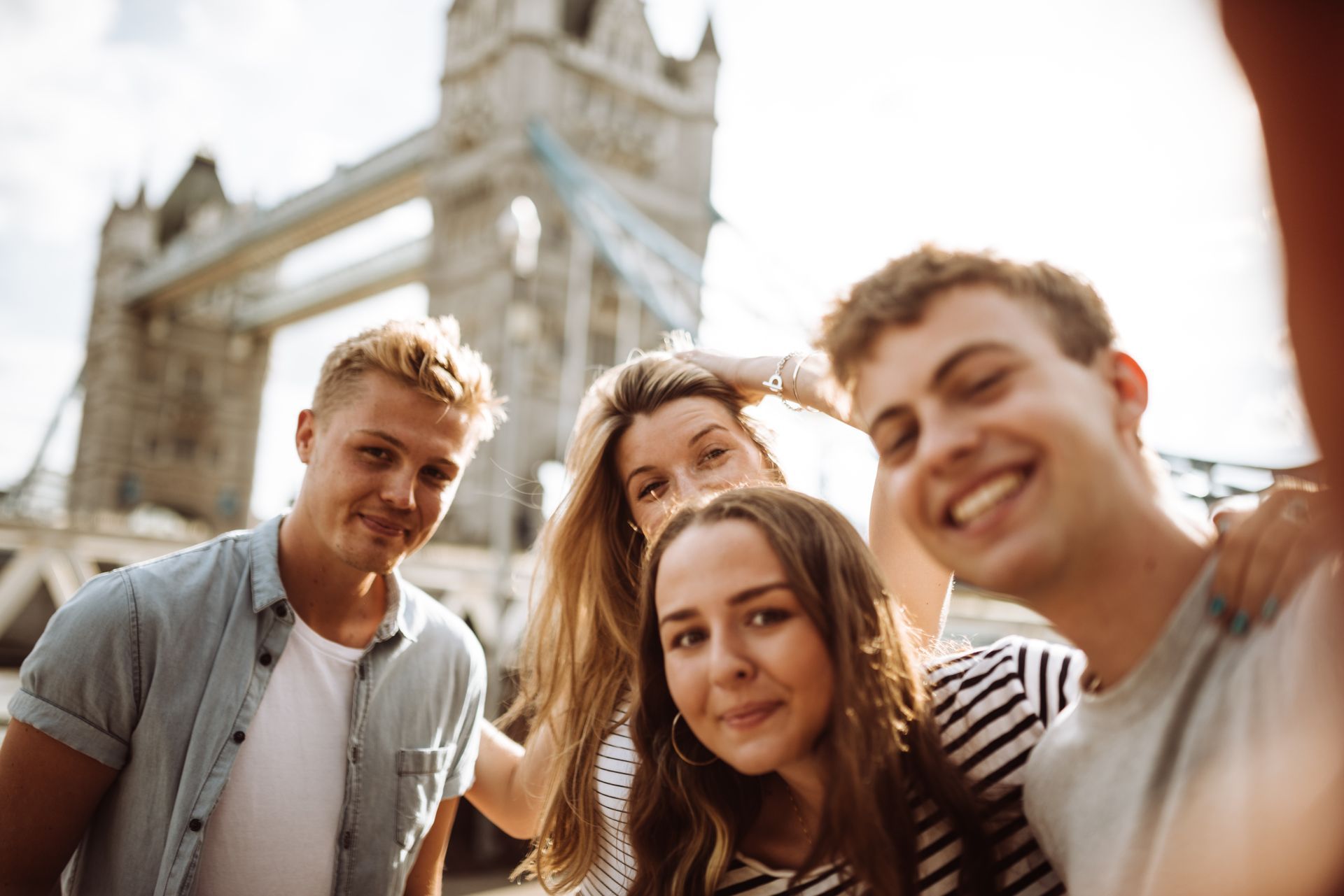 Een groep jongeren poseert voor een foto voor een brug.