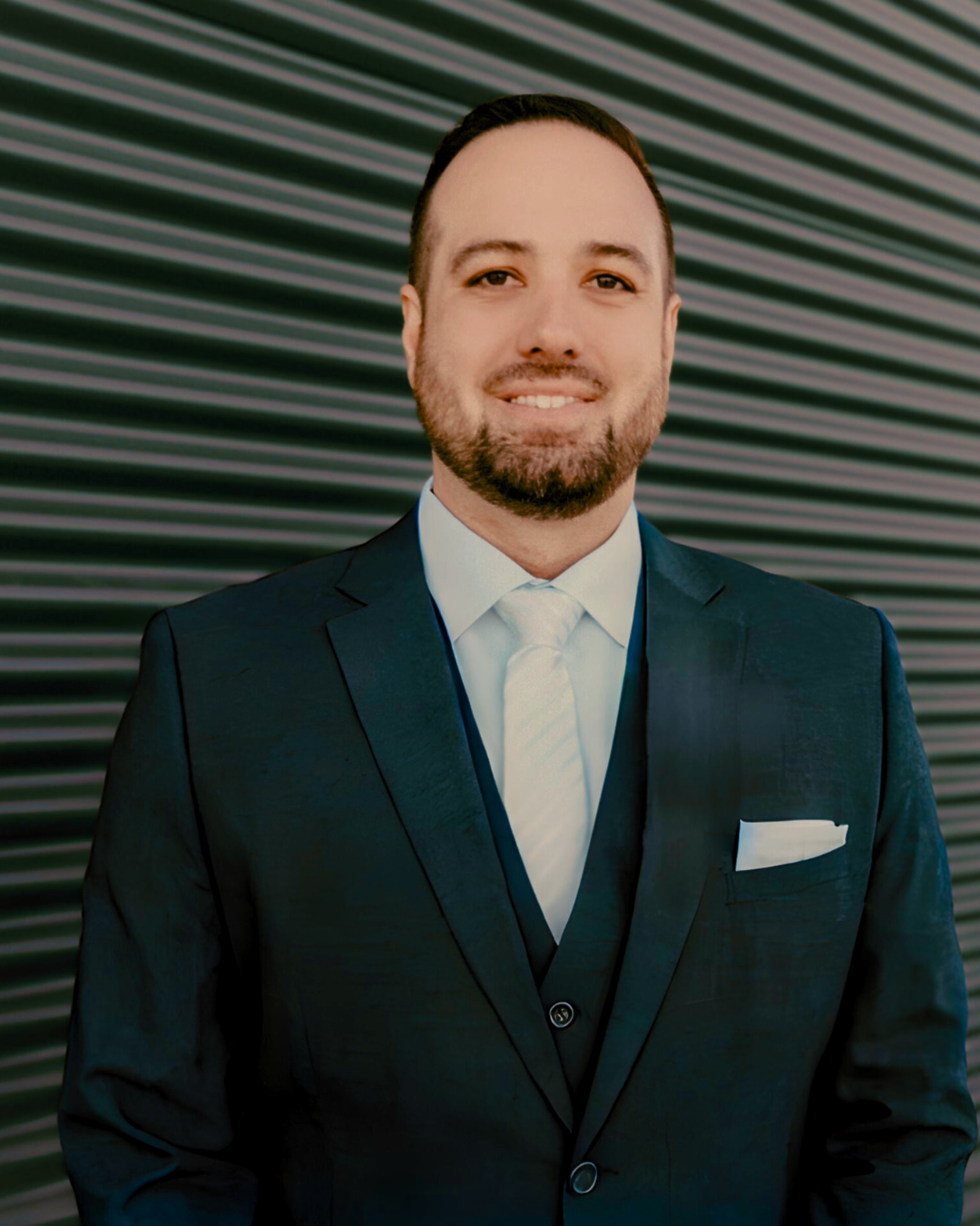 A man in a suit and tie is standing in front of a wall.