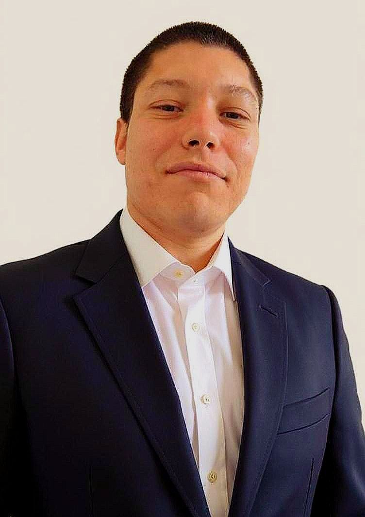 A man in a suit and white shirt is smiling for the camera.