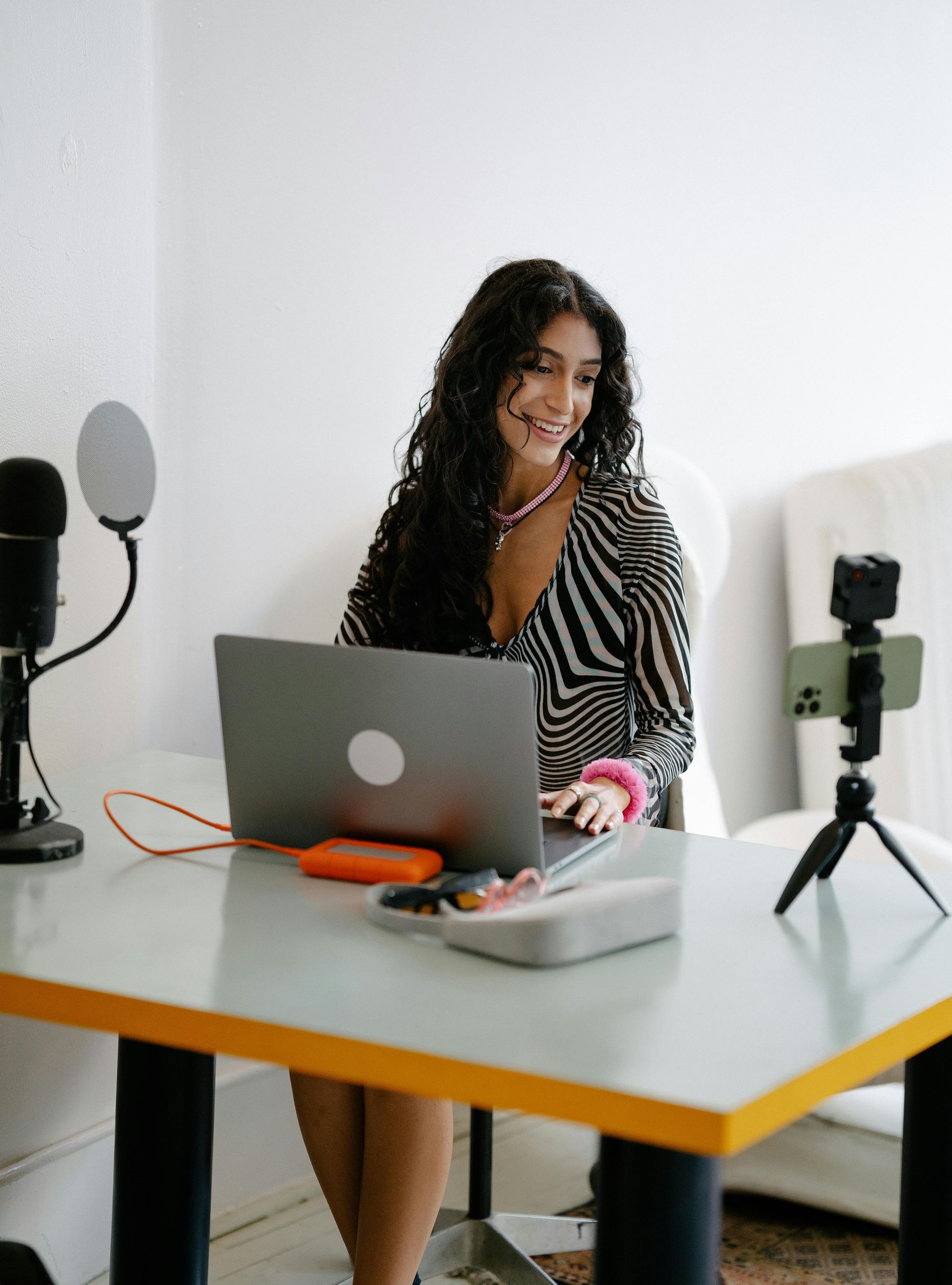 A woman is sitting at a table with a laptop and a microphone.