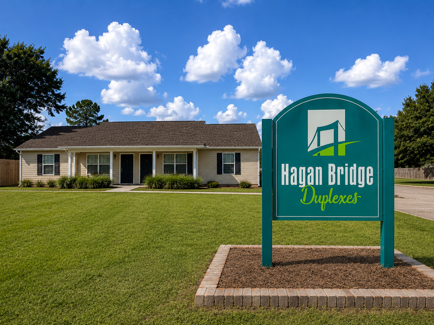 Hagan Bridge Duplexes sign in front of a single-story home under a blue sky