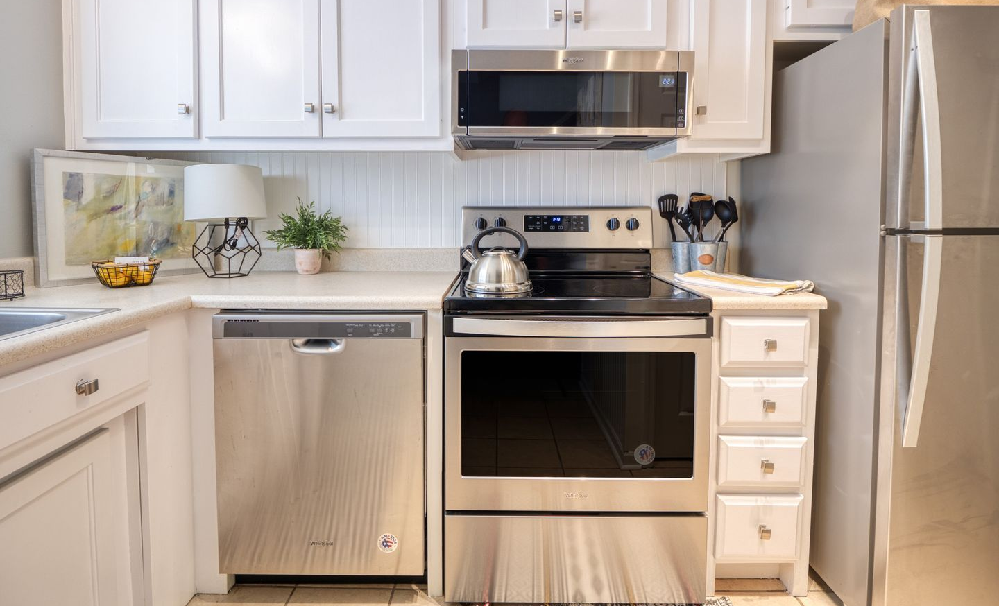 Bright white kitchen with stainless steel appliances and tiled backsplash