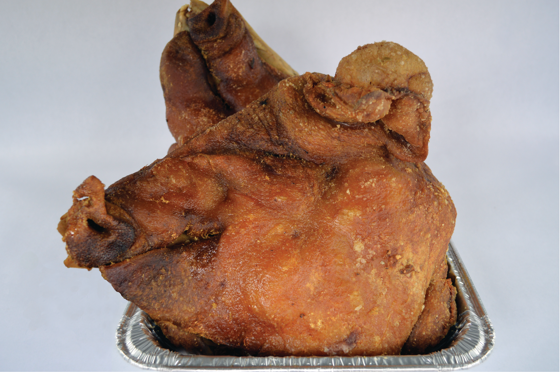 A fried pork head is in a tin foil container