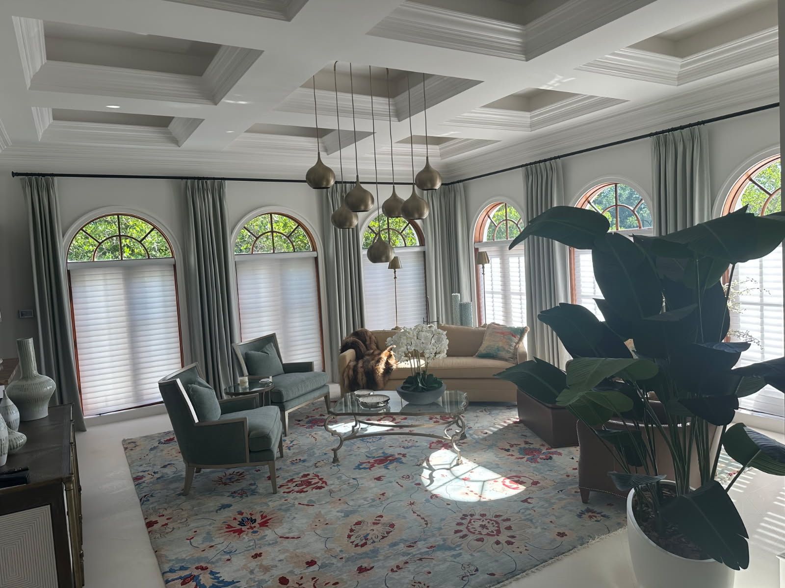 Living room with arched windows, coffered ceiling, gray curtains, and patterned rug.