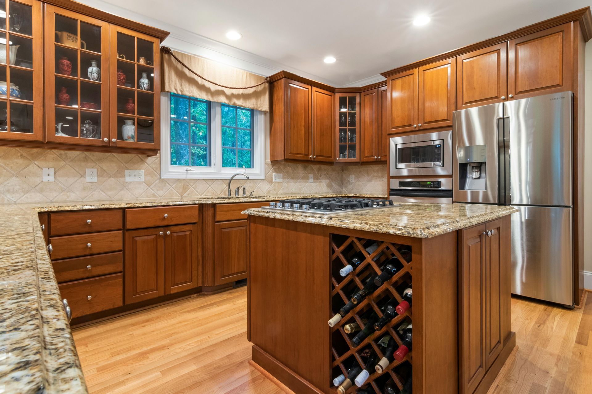 Wooden kitchen with granite countertops, stainless steel appliances, and wine rack.