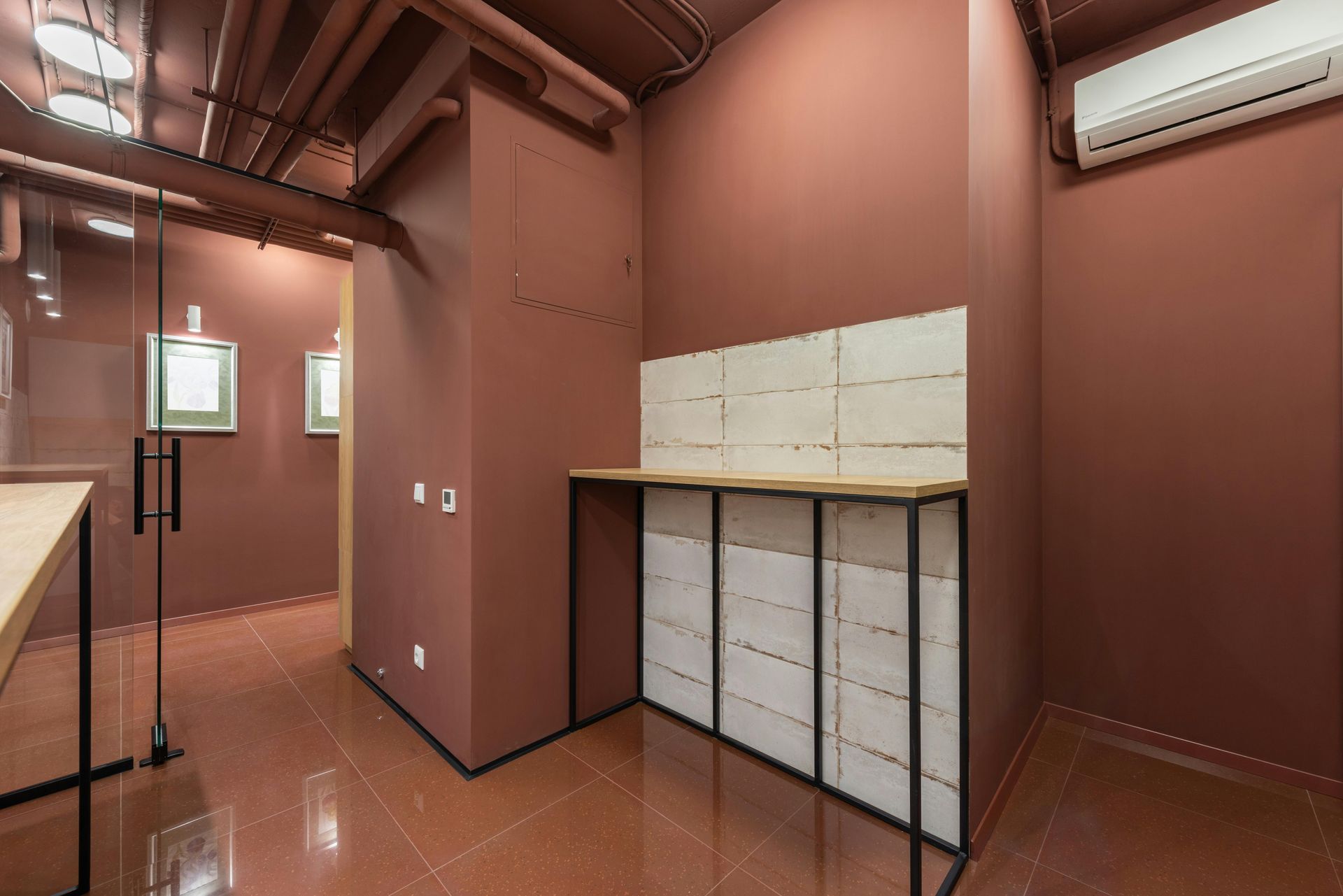 Interior of a room with maroon walls, a white countertop, and glass door.