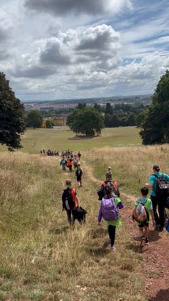People walking along a path in a wooded area, trees overhead.