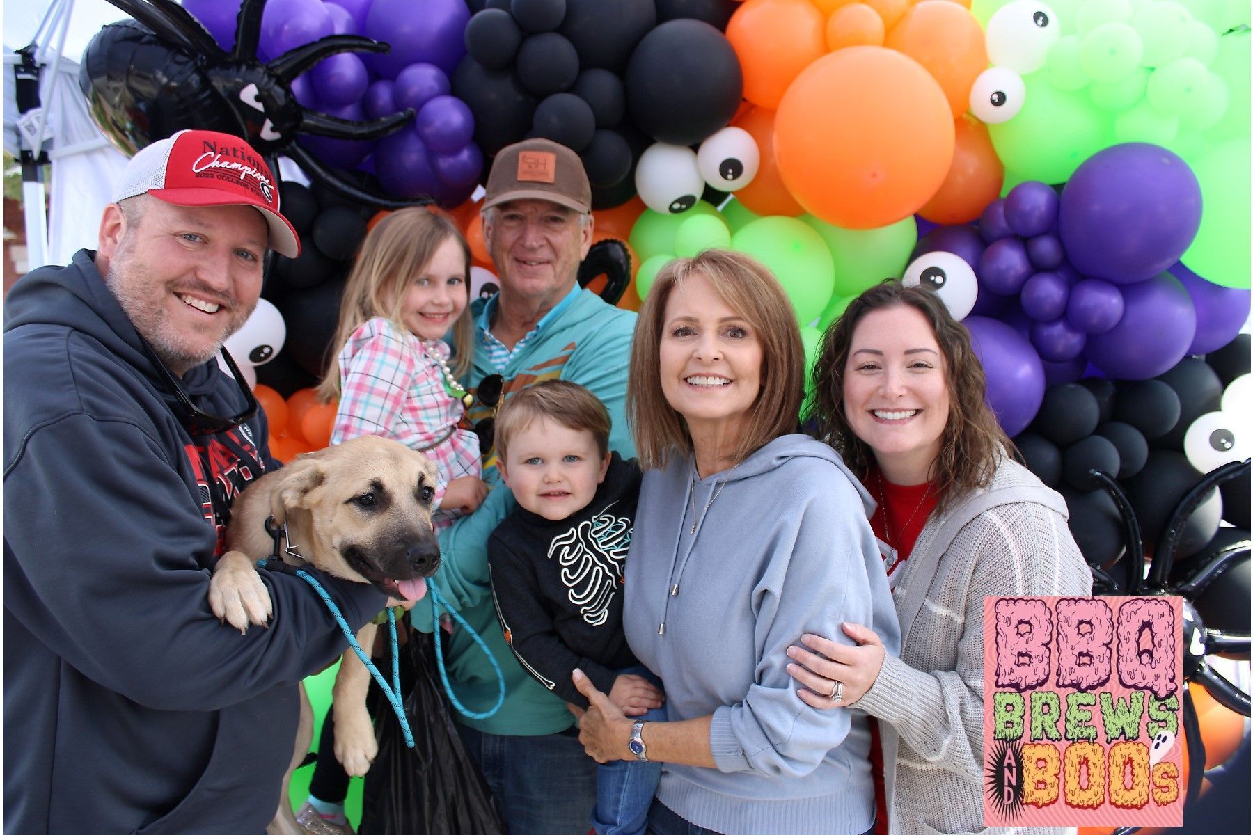 A group of people posing for a picture with balloons in the background.