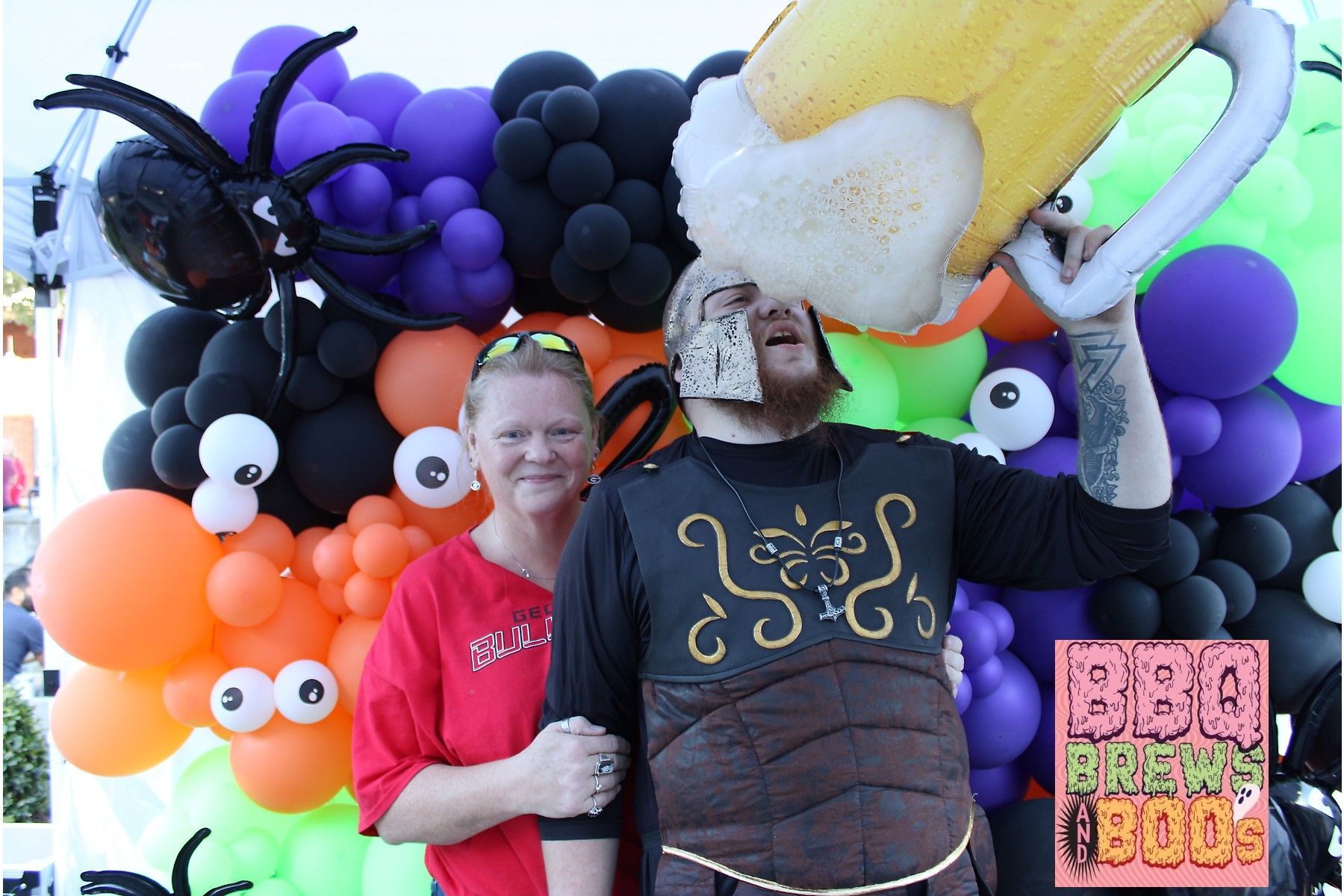 A man in a beer costume is standing next to a woman in front of balloons
