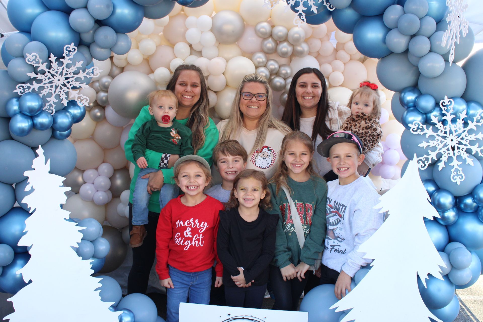 A group of people are posing for a picture in front of a wall of balloons.