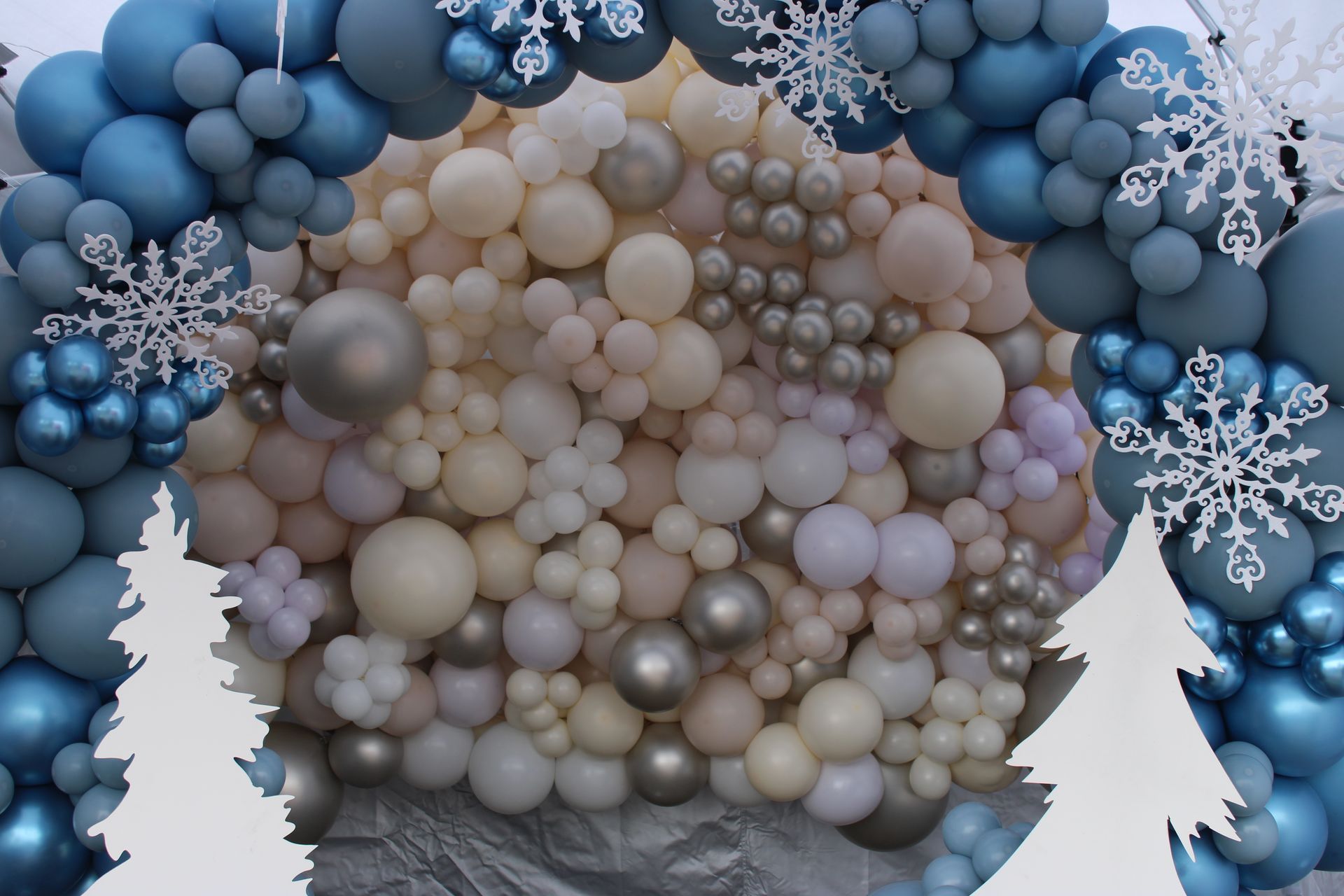 A wall of balloons with snowflakes and trees in the background