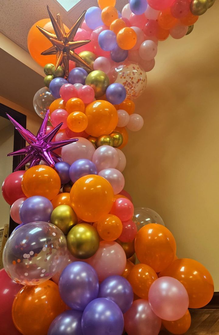 A bunch of colorful balloons are hanging from the ceiling in a room.