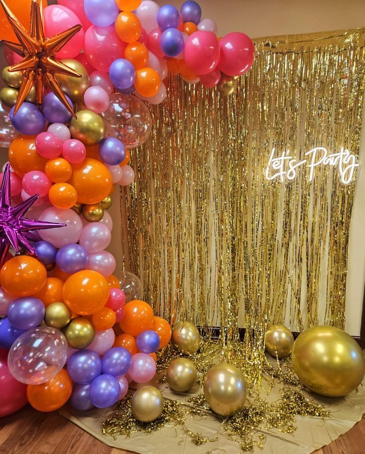 A room filled with balloons and a sign that says `` let 's party ''.
