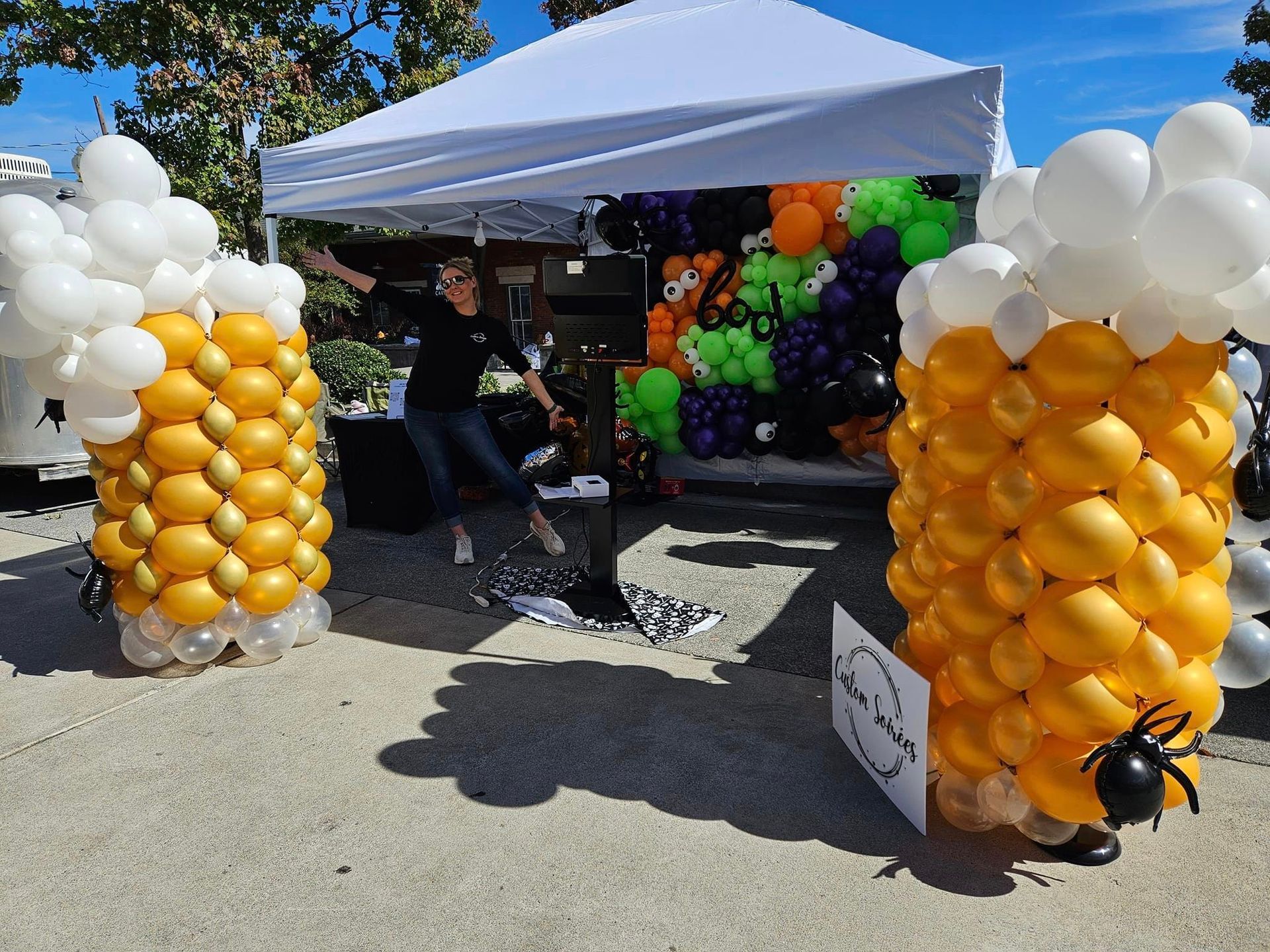 A woman is standing in front of a tent decorated with balloons.