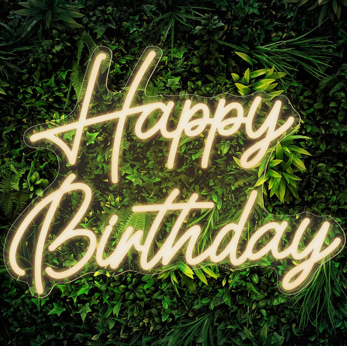 A neon sign that says happy birthday is surrounded by greenery