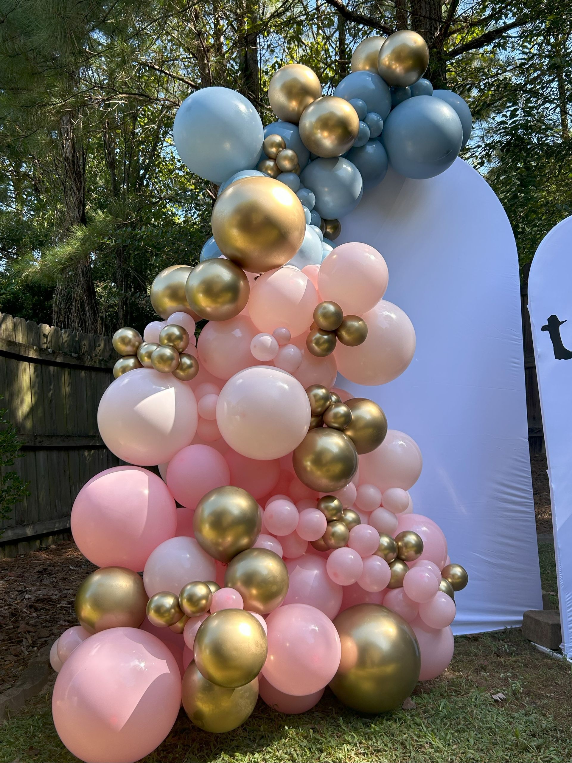 A bunch of pink and gold balloons are sitting on top of each other on the grass.