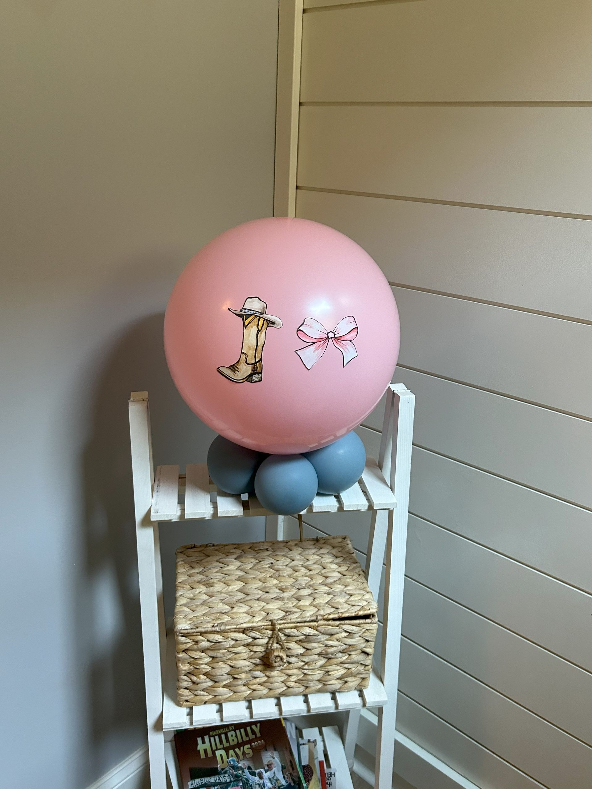 A pink balloon with pigs on it is on a shelf
