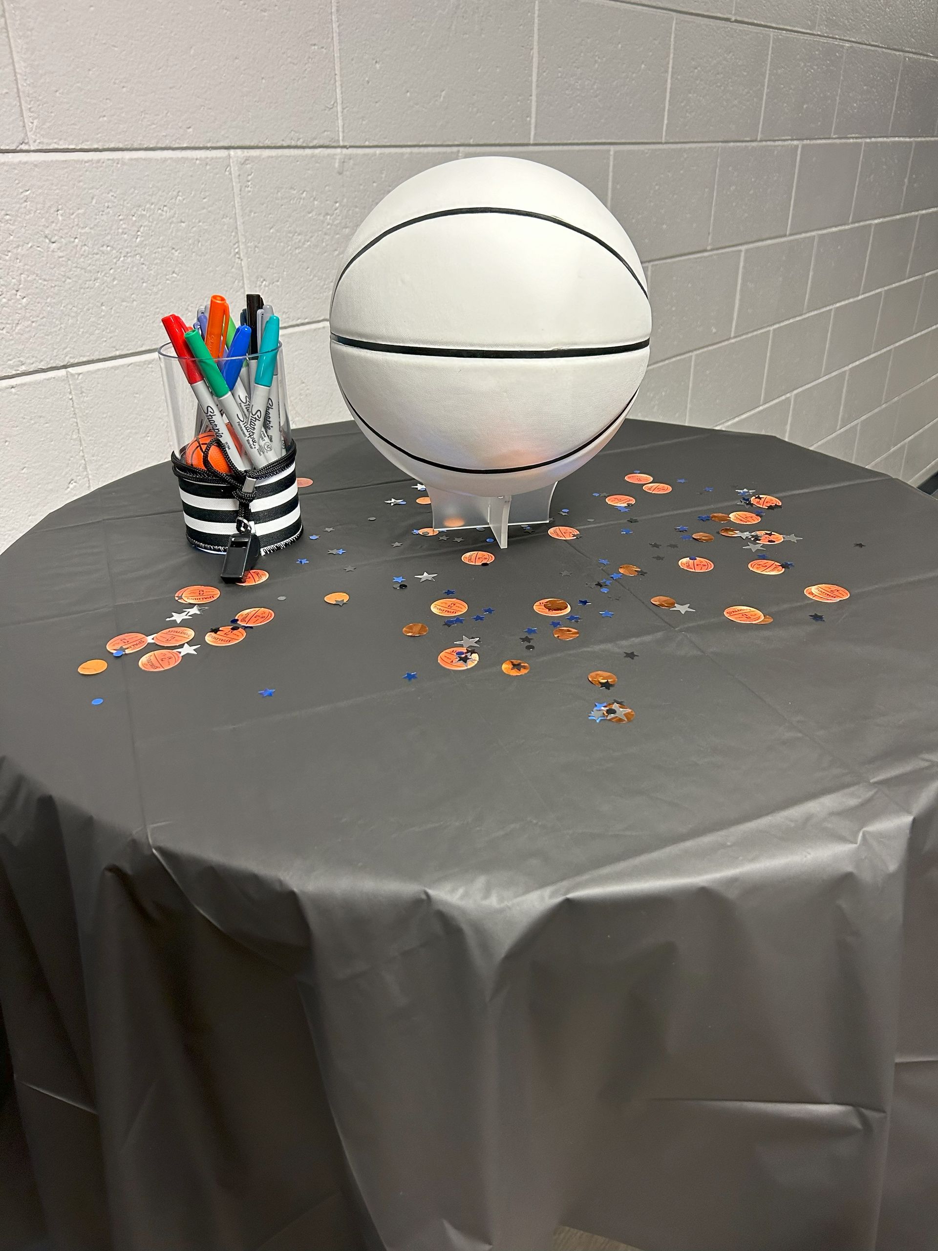 A basketball is sitting on a table with markers and confetti.