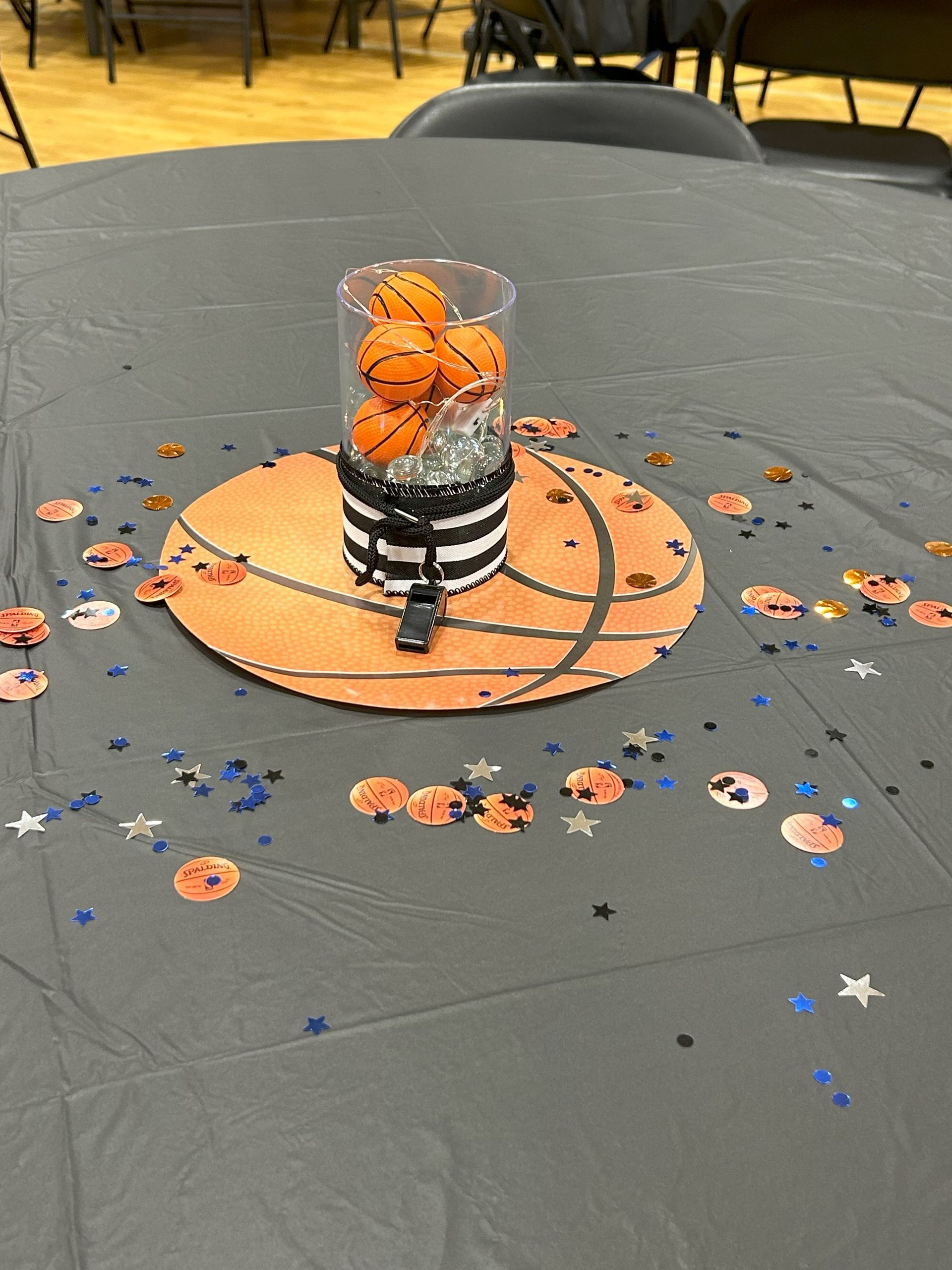 A table with a basketball shaped vase filled with basketballs