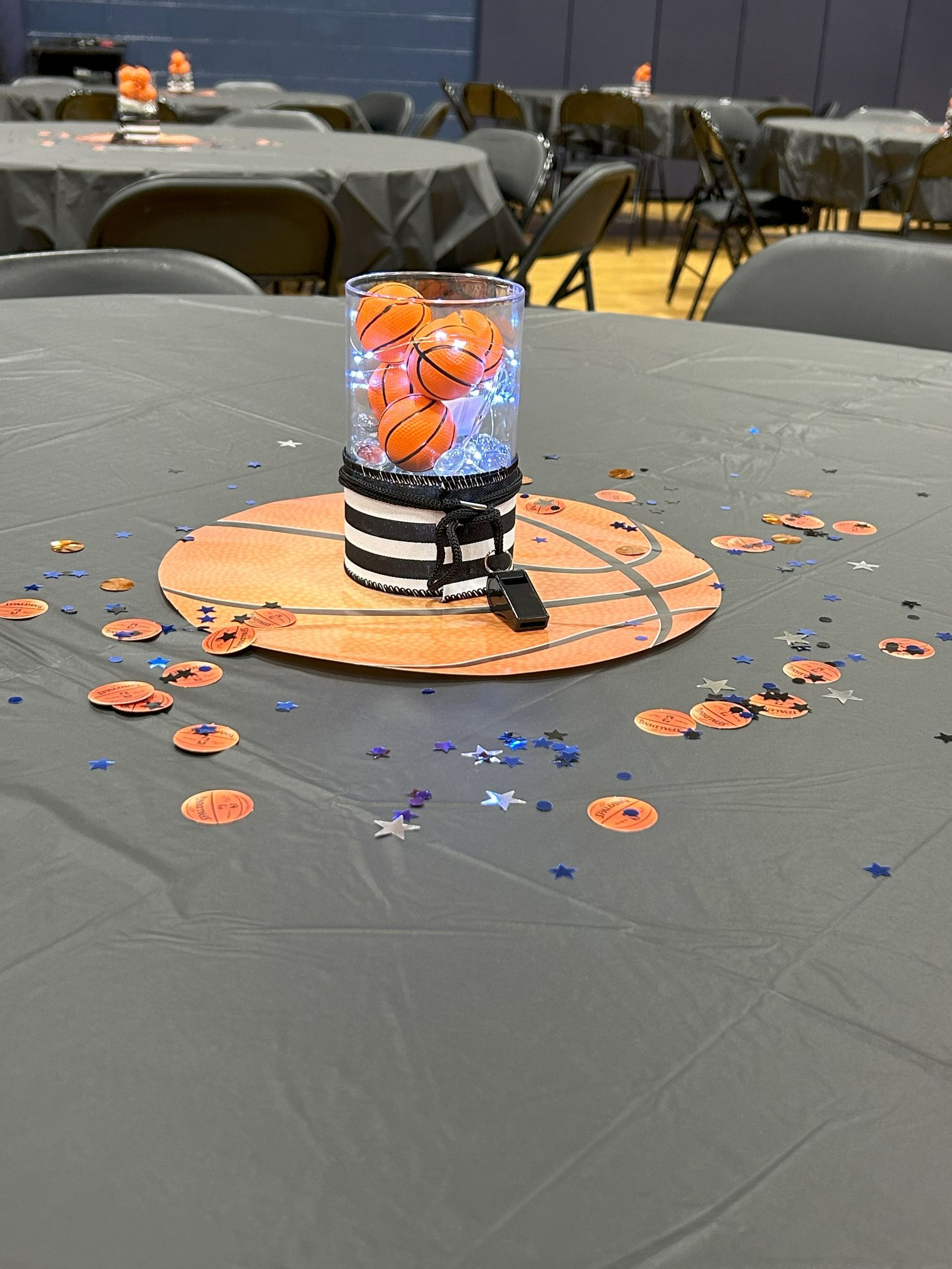 A table with a vase filled with basketballs on it.