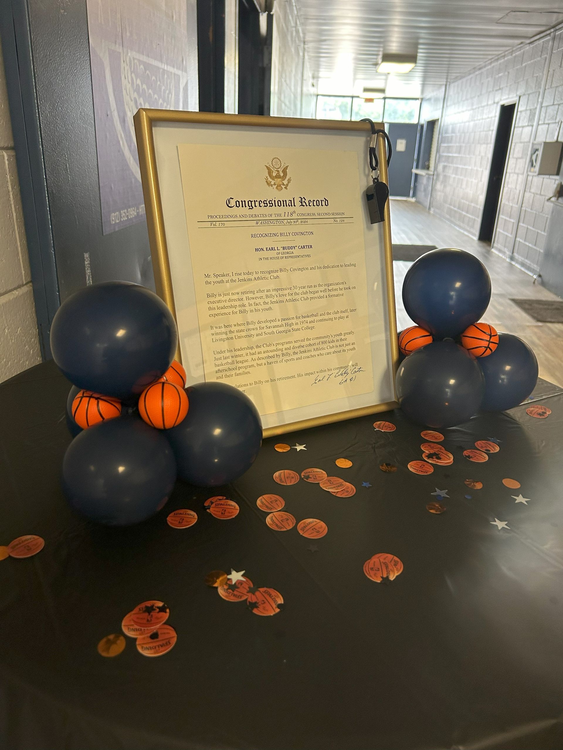 A framed certificate is surrounded by balloons and basketballs on a table.