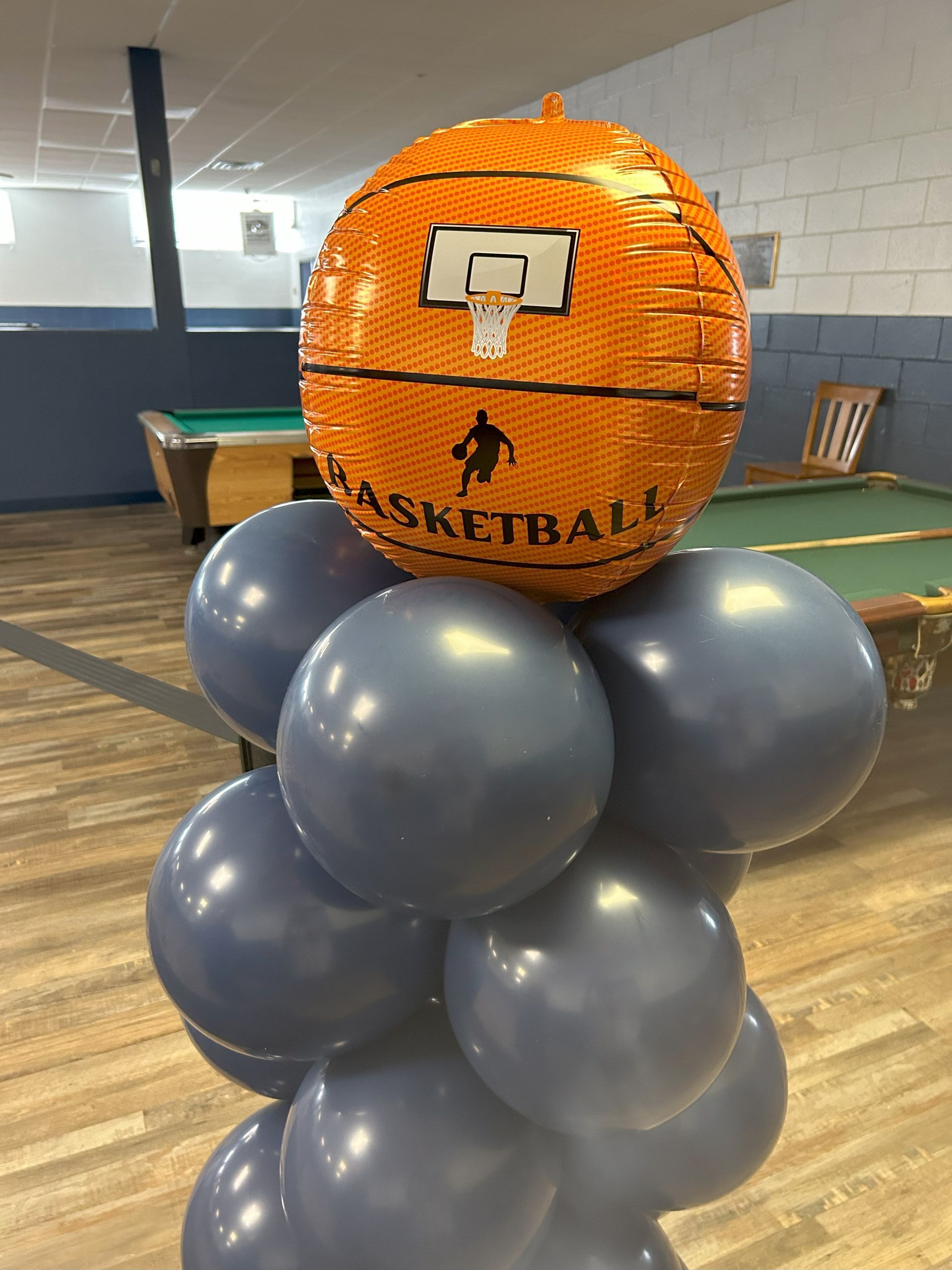 A basketball balloon is sitting on top of a bunch of balloons